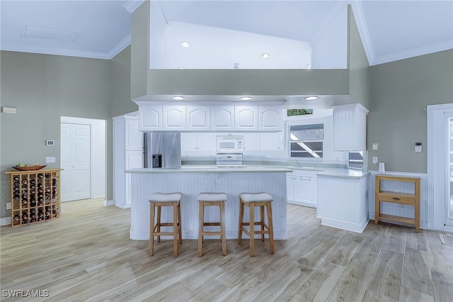 10800 Habitat Cir, Bokeelia, FL 33922 - kitchen featuring stainless steel fridge, crown molding, a towering ceiling, white microwave, and white cabinets