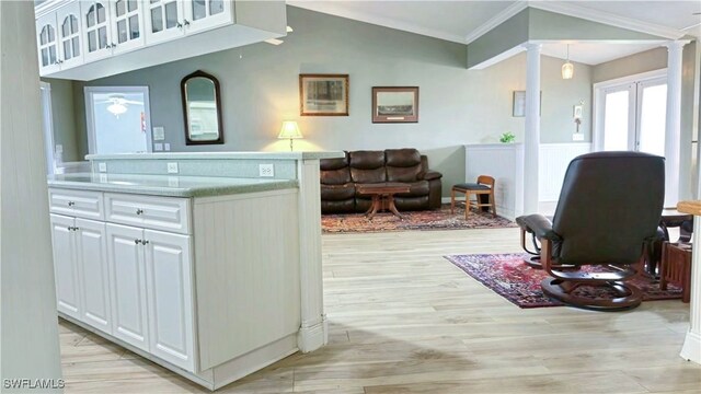 10800 Habitat Cir, Bokeelia, FL 33922 - kitchen with decorative columns, crown molding, white cabinetry, light countertops, and glass insert cabinets