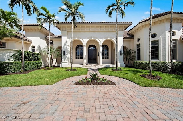 mediterranean / spanish-style home featuring a front yard, a tile roof, and stucco siding