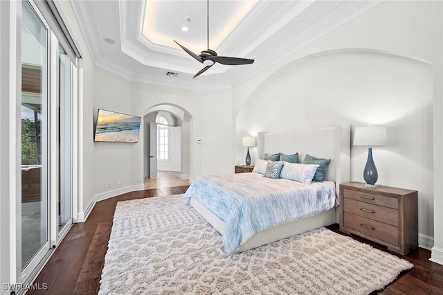 bedroom with crown molding, arched walkways, dark wood finished floors, and a tray ceiling