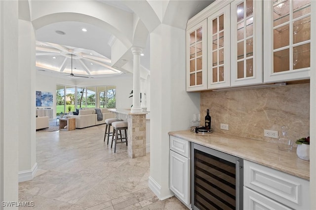 bar featuring baseboards, decorative backsplash, wine cooler, a bar, and recessed lighting