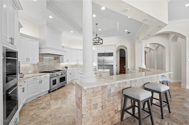 kitchen featuring premium range hood, decorative backsplash, high end appliances, a large island with sink, and crown molding