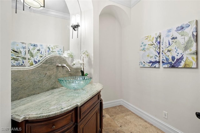 bathroom with ornamental molding, vanity, and baseboards