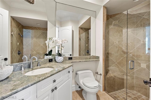 bathroom with toilet, a stall shower, vanity, baseboards, and tile patterned floors