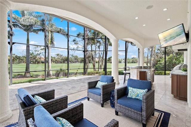 view of patio with exterior kitchen, glass enclosure, a grill, and an outdoor living space