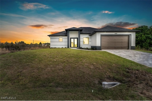 view of front of house with a front lawn, decorative driveway, an attached garage, and stucco siding