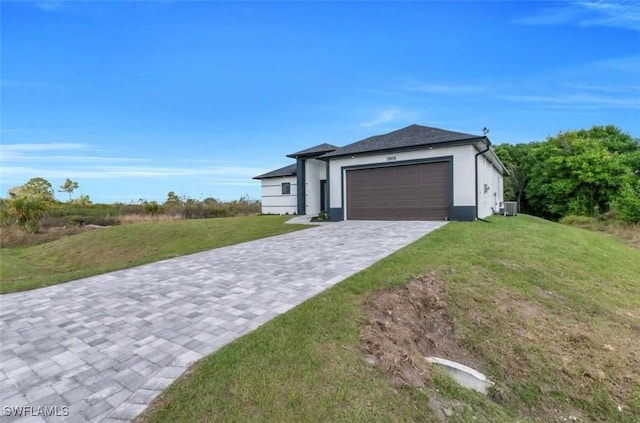 view of front of property with a garage, central AC, decorative driveway, and a front yard