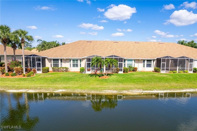 back of property with a lawn and a water view