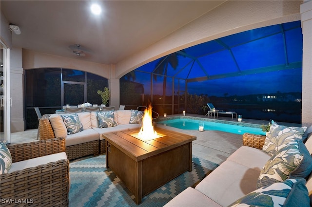 pool at dusk featuring a patio, glass enclosure, and an outdoor living space with a fire pit