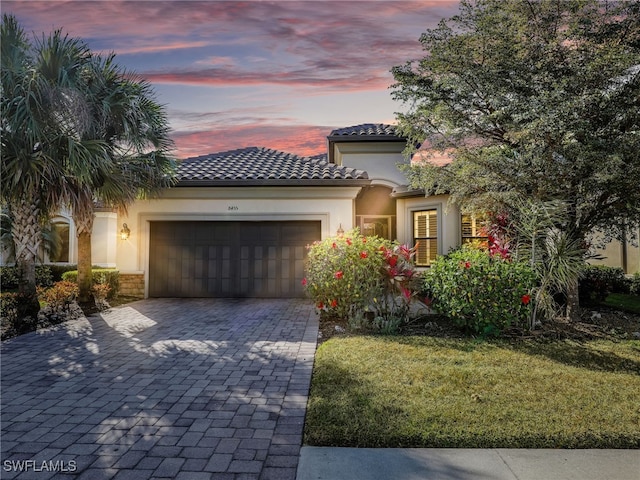 mediterranean / spanish house with a garage and a lawn