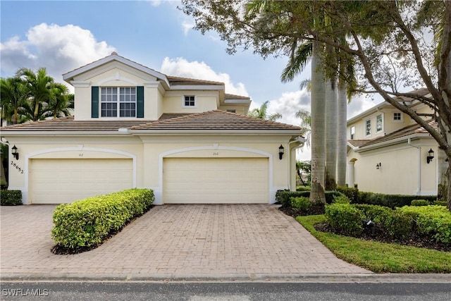 view of front facade with decorative driveway, a tile roof, and stucco siding