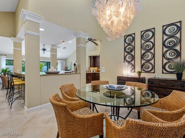 tiled dining room with high vaulted ceiling, ceiling fan with notable chandelier, and ornate columns