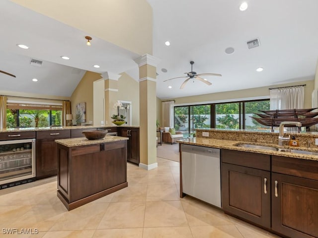 kitchen featuring wine cooler, stainless steel dishwasher, light stone countertops, and sink