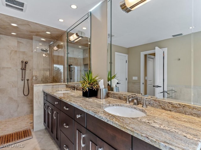 bathroom with a tile shower and vanity