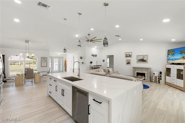 kitchen featuring a lit fireplace, a sink, stainless steel dishwasher, lofted ceiling, and visible vents