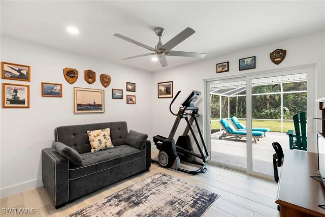 exercise area featuring baseboards, light wood-type flooring, and a ceiling fan