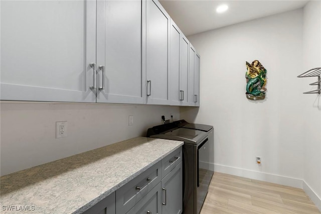 laundry area with washer and clothes dryer, cabinet space, light wood-style floors, and baseboards