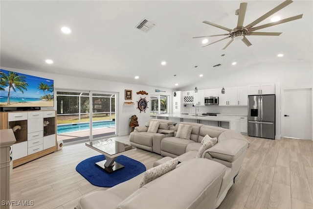 living room featuring visible vents, ceiling fan, light wood-type flooring, and vaulted ceiling