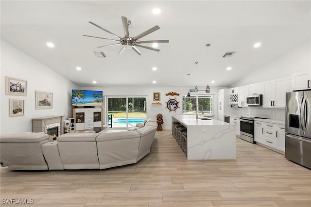 living area with plenty of natural light, wood tiled floor, visible vents, and a ceiling fan