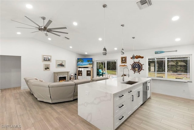 kitchen featuring visible vents, a ceiling fan, a sink, open floor plan, and vaulted ceiling