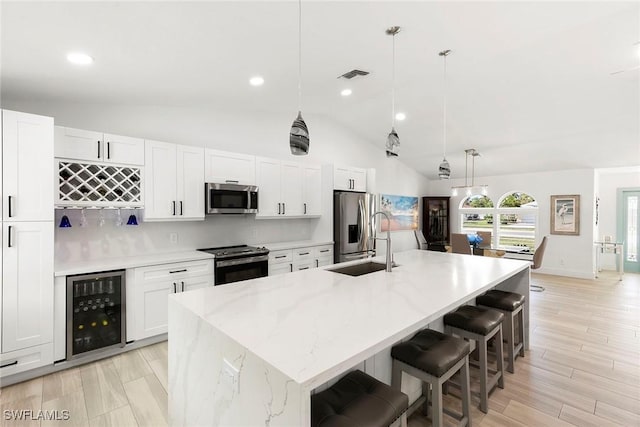 kitchen featuring wine cooler, stainless steel appliances, a center island with sink, white cabinetry, and a sink