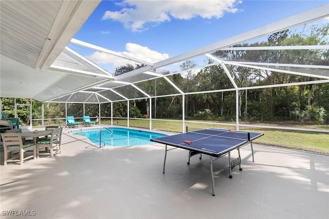 pool with a lawn, glass enclosure, and a patio