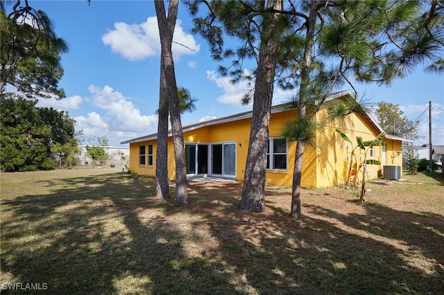 back of house with a yard and central air condition unit