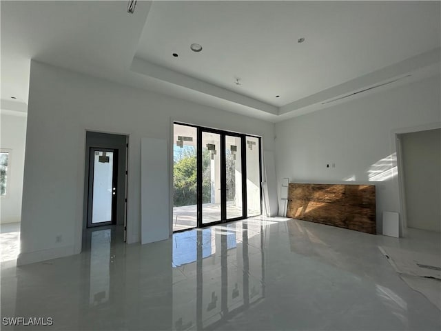 unfurnished living room featuring a tray ceiling and french doors