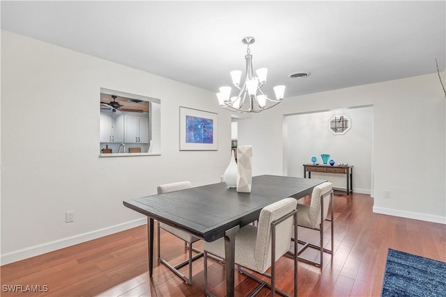 dining area featuring ceiling fan with notable chandelier and dark hardwood / wood-style flooring