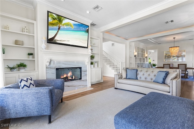 living room with visible vents, crown molding, a premium fireplace, and wood finished floors