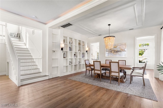 dining room featuring built in shelves, wood finished floors, visible vents, stairway, and crown molding