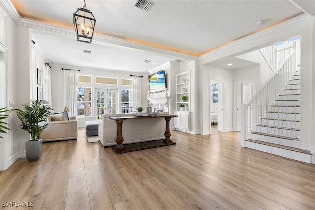 living room with light wood-type flooring, stairs, visible vents, and ornamental molding