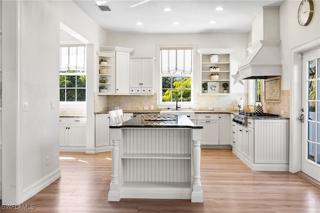 kitchen featuring custom exhaust hood, open shelves, visible vents, white cabinets, and a kitchen island