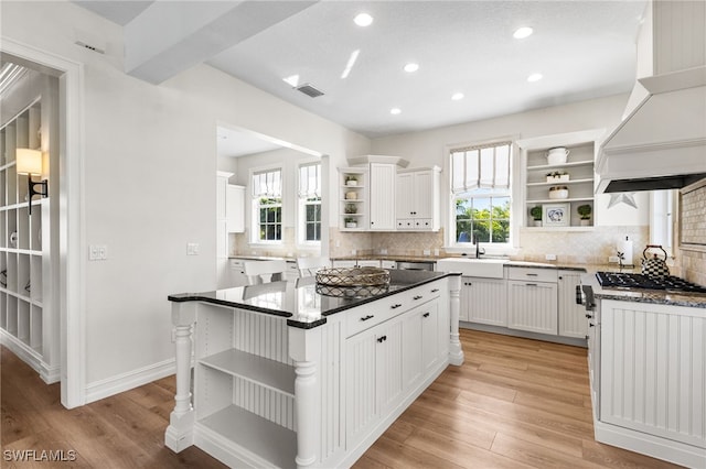 kitchen with premium range hood, visible vents, white cabinetry, a center island, and open shelves