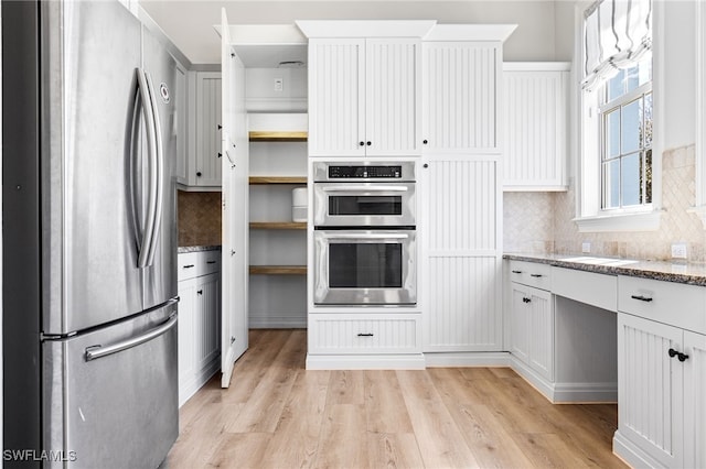 kitchen featuring light stone counters, open shelves, light wood-style flooring, appliances with stainless steel finishes, and white cabinets