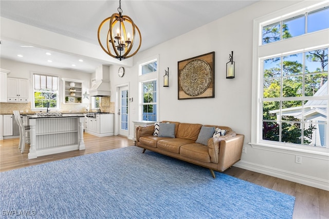 living room with light wood-style floors, recessed lighting, a notable chandelier, and baseboards