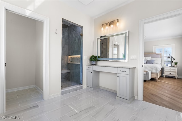 ensuite bathroom with ensuite bathroom, a shower stall, vanity, and baseboards