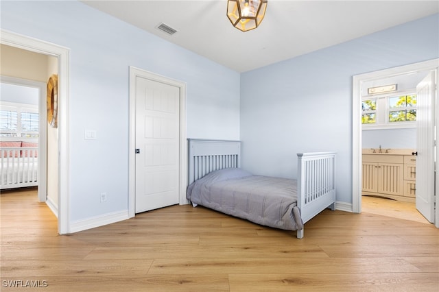 bedroom with light wood-style floors, visible vents, baseboards, and multiple windows