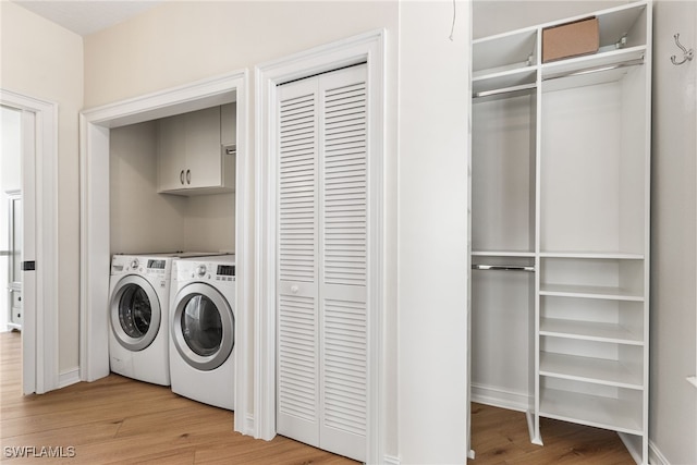 laundry room featuring separate washer and dryer, wood finished floors, and cabinet space