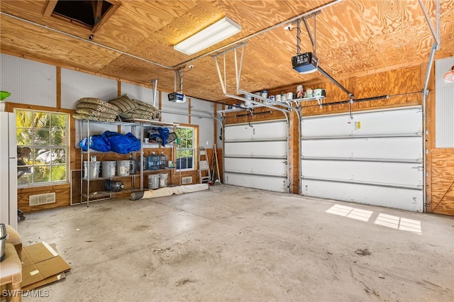 garage with a garage door opener, freestanding refrigerator, and visible vents