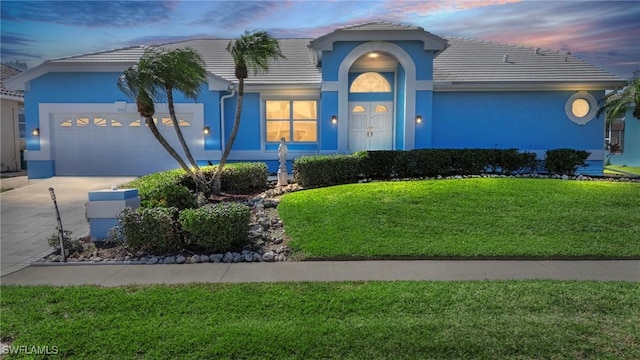 view of front of home with a garage and a lawn