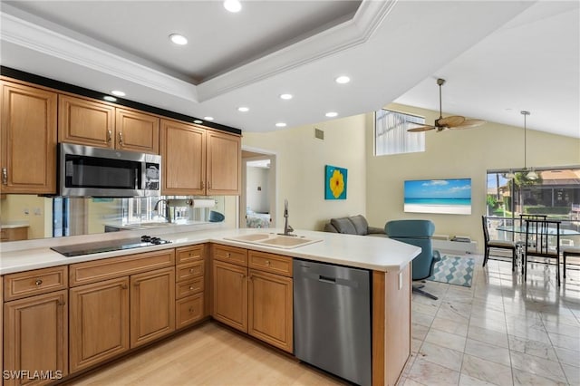 kitchen featuring sink, appliances with stainless steel finishes, hanging light fixtures, a tray ceiling, and kitchen peninsula