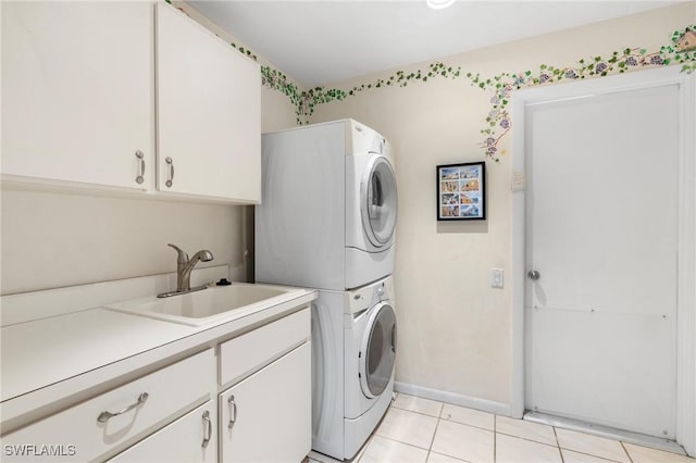 washroom with sink, light tile patterned flooring, cabinets, and stacked washing maching and dryer