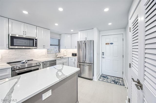 kitchen featuring high quality appliances, tasteful backsplash, sink, white cabinets, and light stone counters