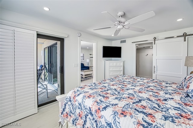 bedroom with ceiling fan, a barn door, light hardwood / wood-style floors, and access to exterior