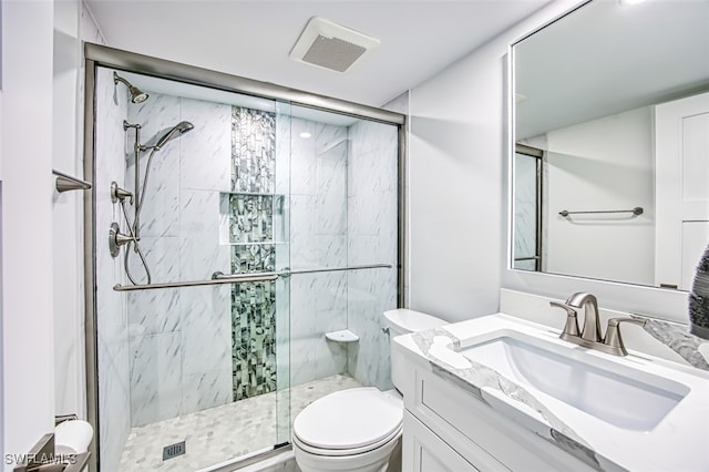 bathroom featuring a shower with door, vanity, and toilet