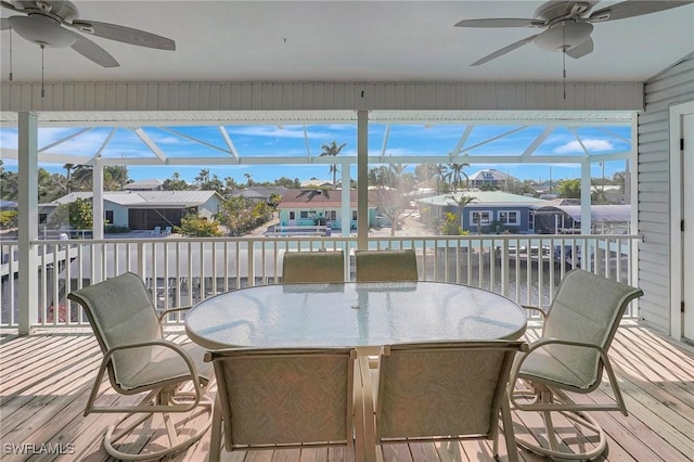 sunroom with outdoor dining area, a residential view, and a ceiling fan