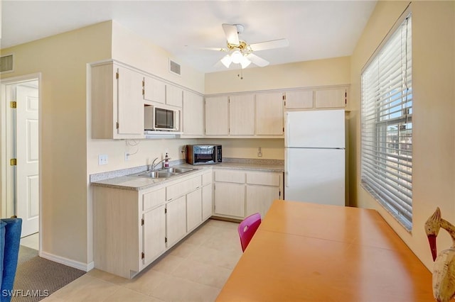 kitchen with freestanding refrigerator, a ceiling fan, visible vents, stainless steel microwave, and a sink