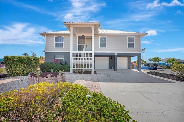 coastal inspired home with a porch, metal roof, a garage, and concrete driveway