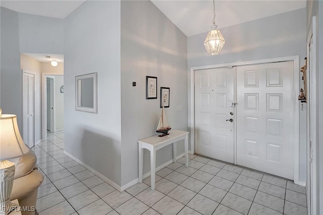 foyer with light tile patterned floors, baseboards, and vaulted ceiling